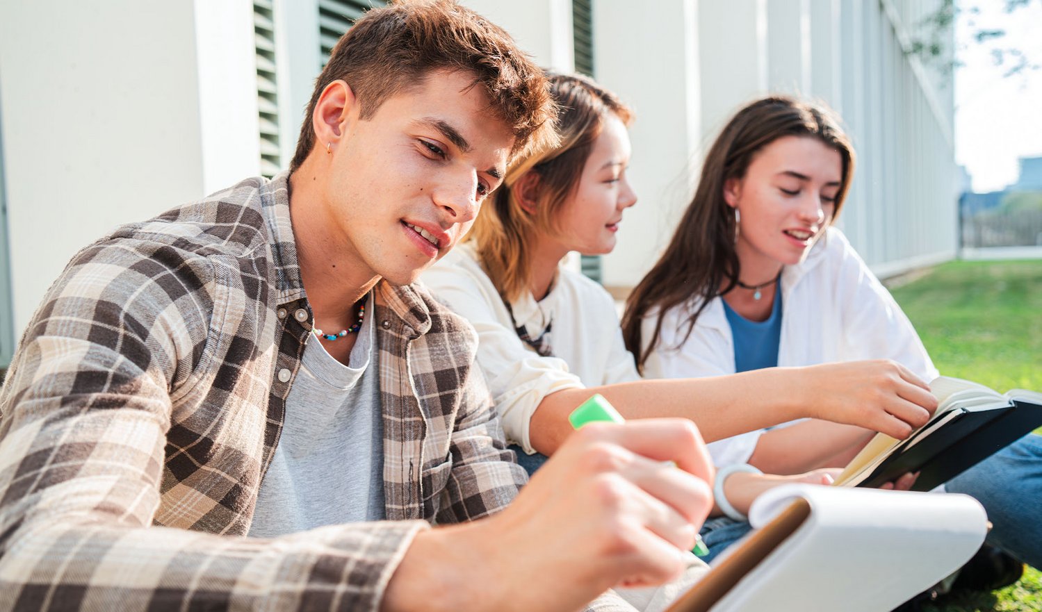Das Foto zeigte mehrere Schüler:innen, die in der Natur in ihrem Buch wichtige Passagen markieren.