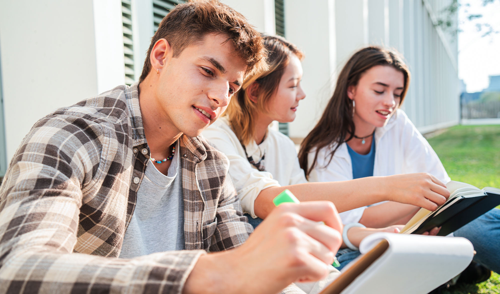 Das Foto zeigte mehrere Schüler:innen, die in der Natur in ihrem Buch wichtige Passagen markieren.
